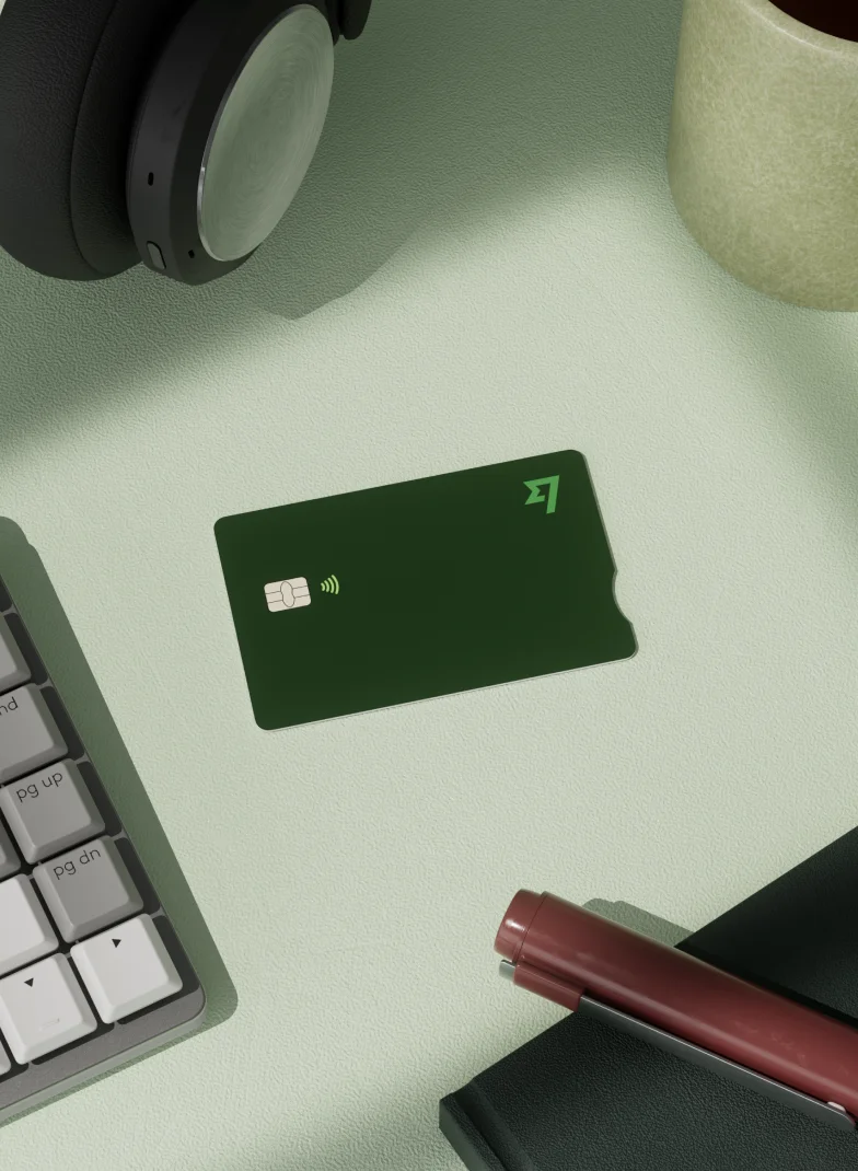 Tarjeta de icono Wise verde oscuro sobre un escritorio verde claro rodeado de accesorios de oficina y un bolígrafo.
