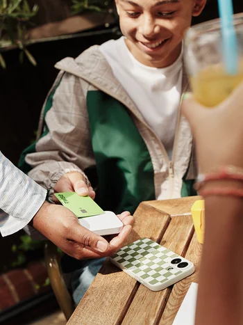 Close-up of a person at a café paying with a Wise card.