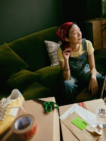 Woman sitting on a green sofa surrounded by craft equipment.