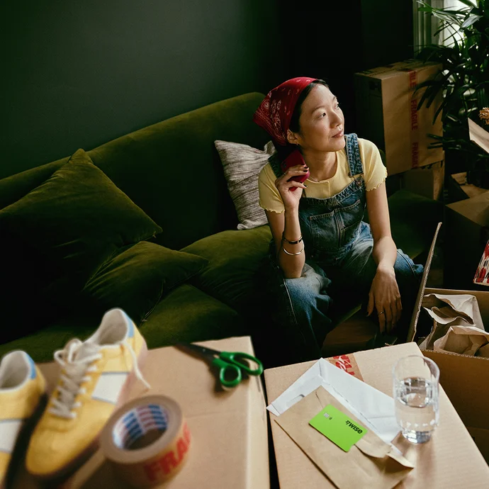 Woman sitting on a green sofa surrounded by craft equipment.