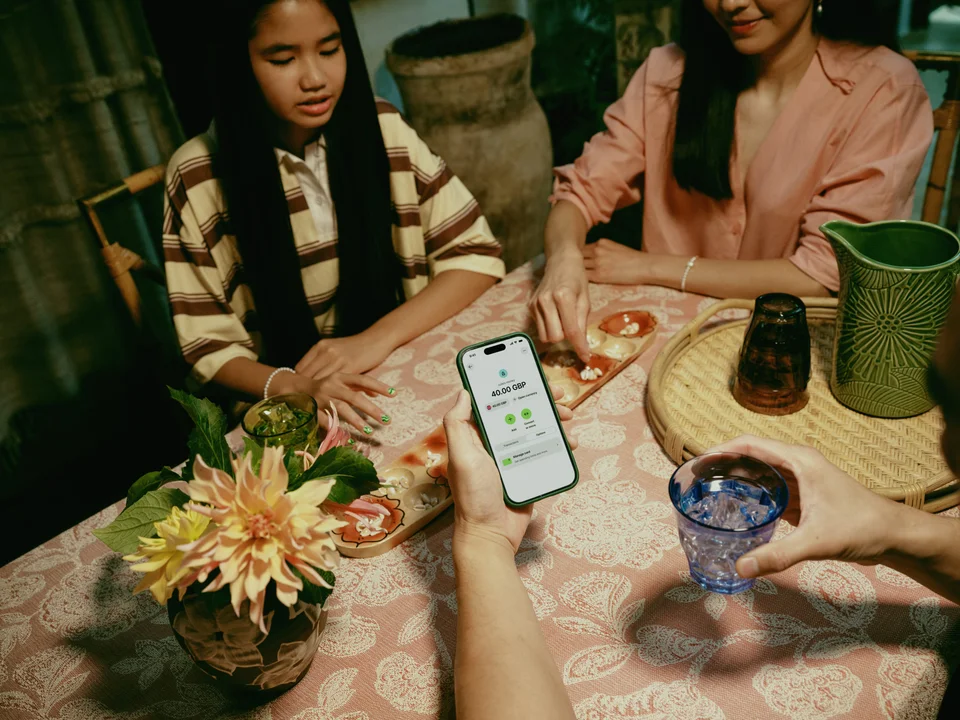 Eine Person, die am Esstisch sitzt und ein Smartphone hält