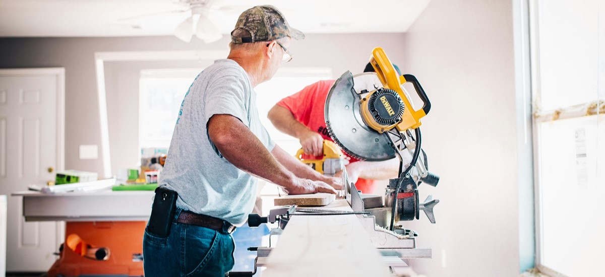 Builders using a circular saw on a workbench in a newly built house