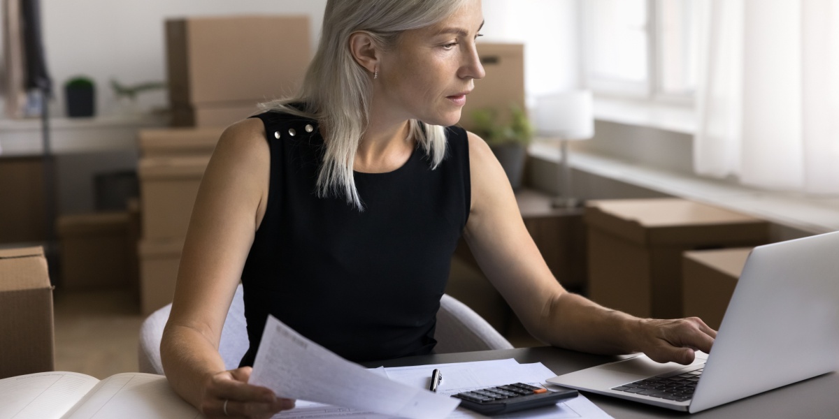 woman-looking-at-laptop-holding-documents