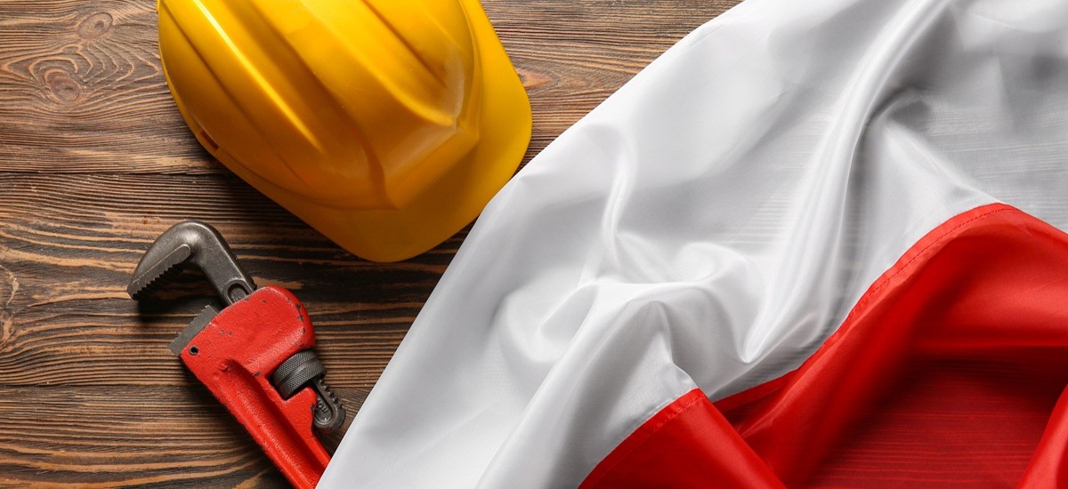 construction tools and hard hat on top of Polish flag