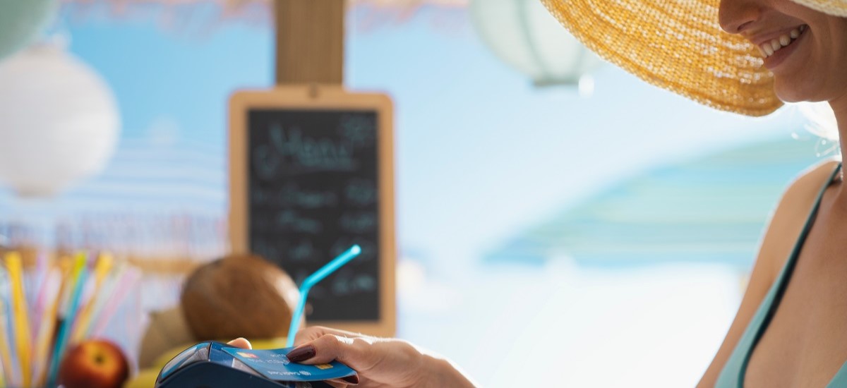 Woman at beach bar paying using a contactless credit card