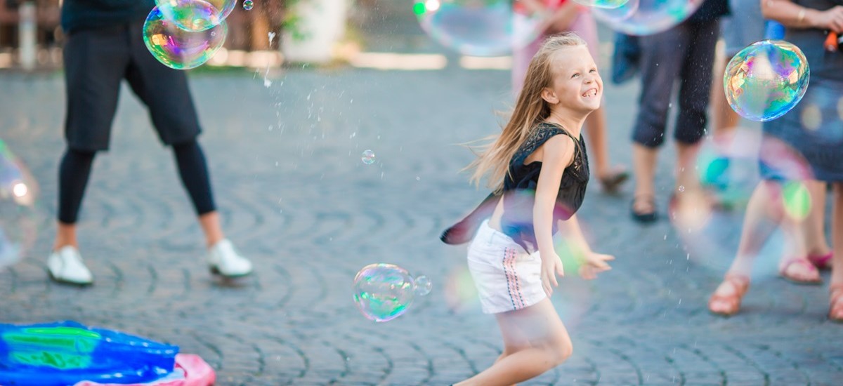 young girl running through a piazza in Rome chasing bubbles