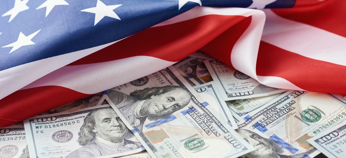 US dollars cash bank notes next to American flag