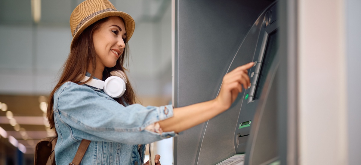 young-stylish-travelling-woman-withdrawing-money-atm