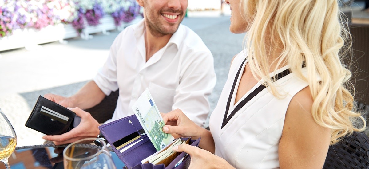 Couple on holiday paying with Euros at an outdoor seating area of a restuarant