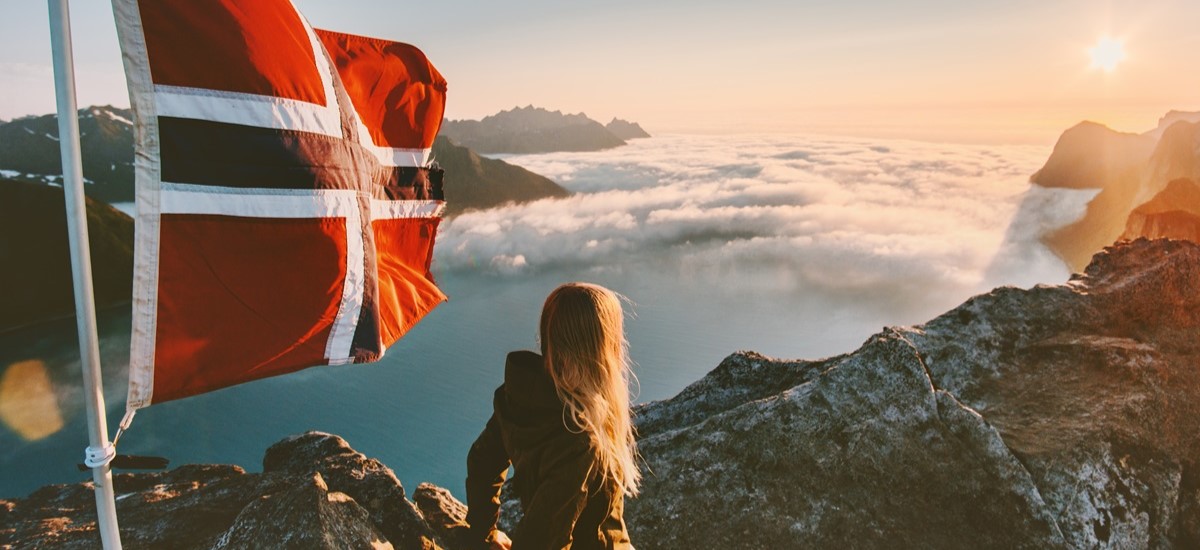 Tourist in the Fjords on top of a mountain with a Norwegian flag