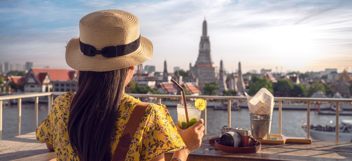Woman in a hat with back to camera at Wat arun pagoda with sunset