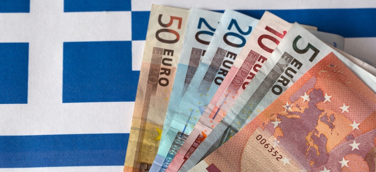 Euro bank notes fanned out on a Greek flag
