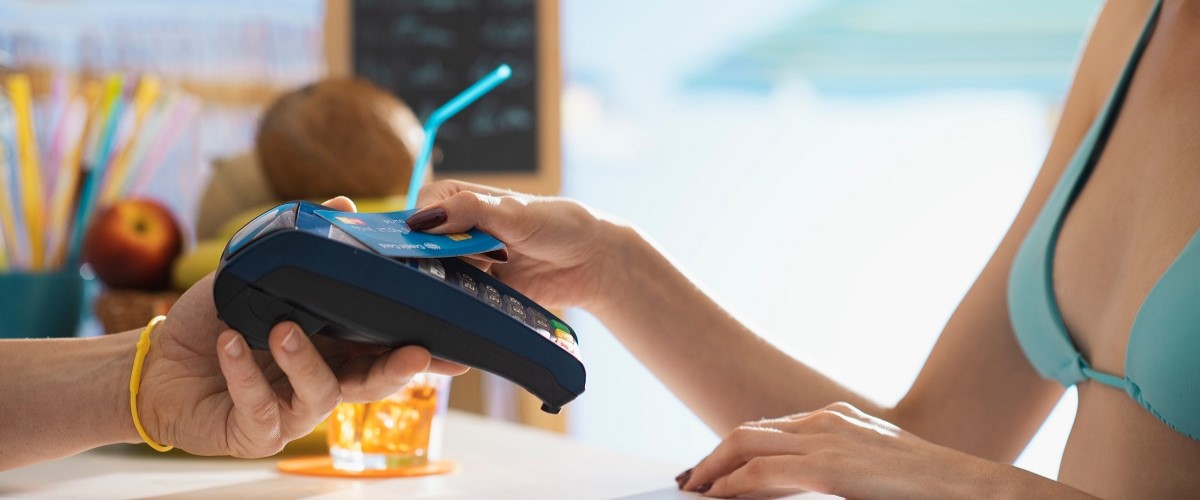 A woman pays for a drink at a beach bar using contactless