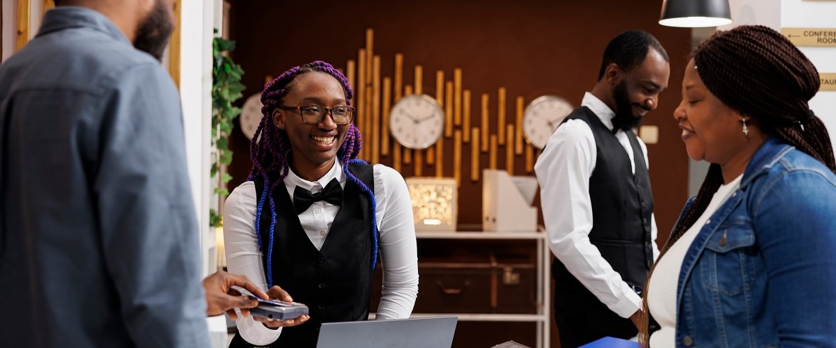 Black couple at a hotel reception paying for their stay on a card