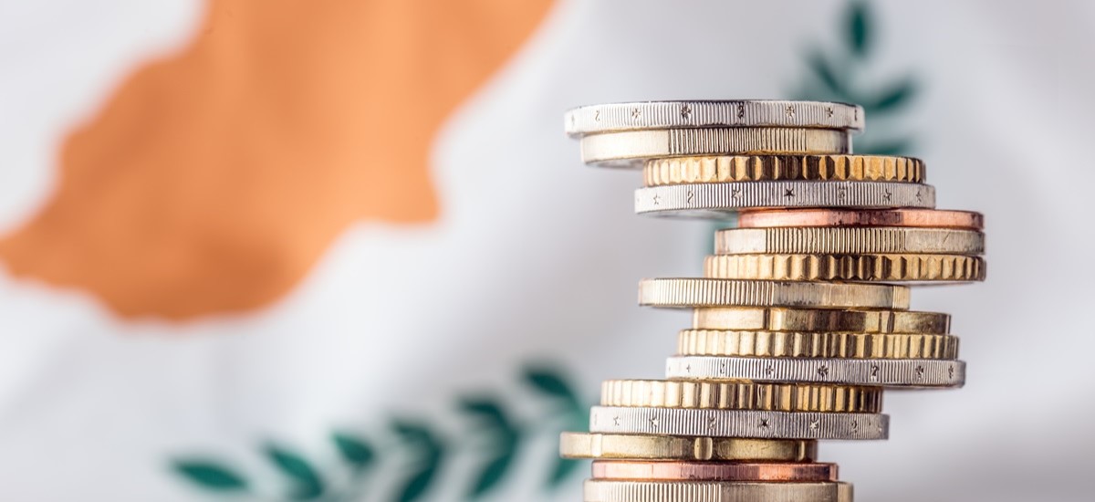 Close up of pile of Euro coins in front of the flag of Cyprus