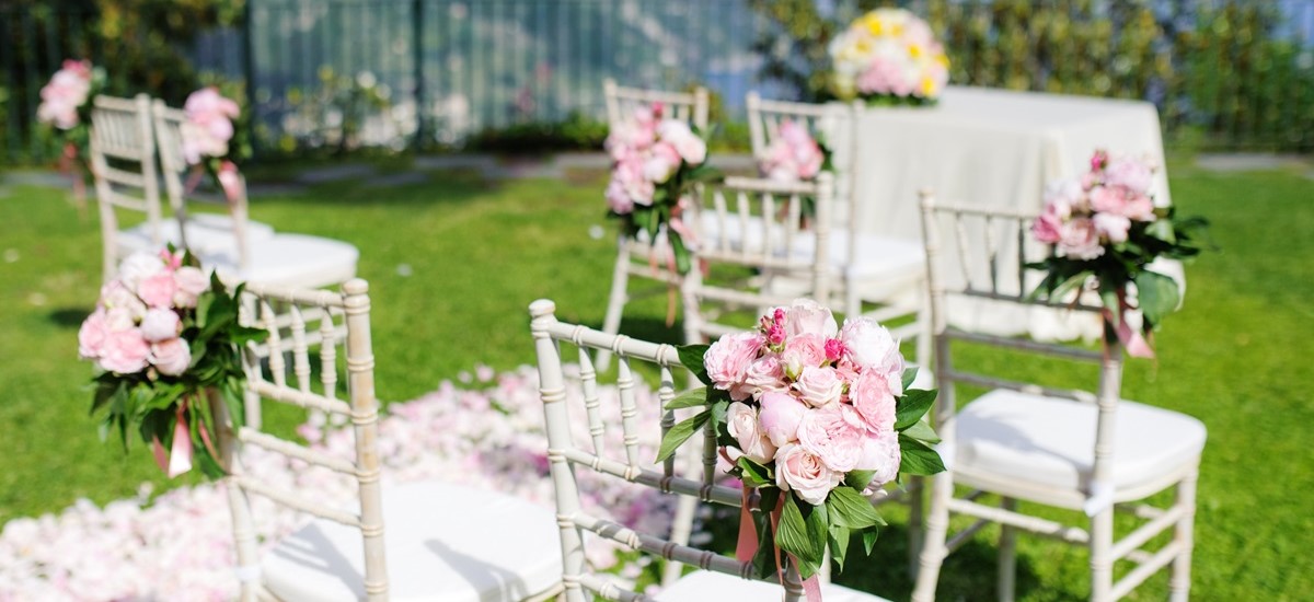 outdoor wedding venue, white chairs decorated with flowers