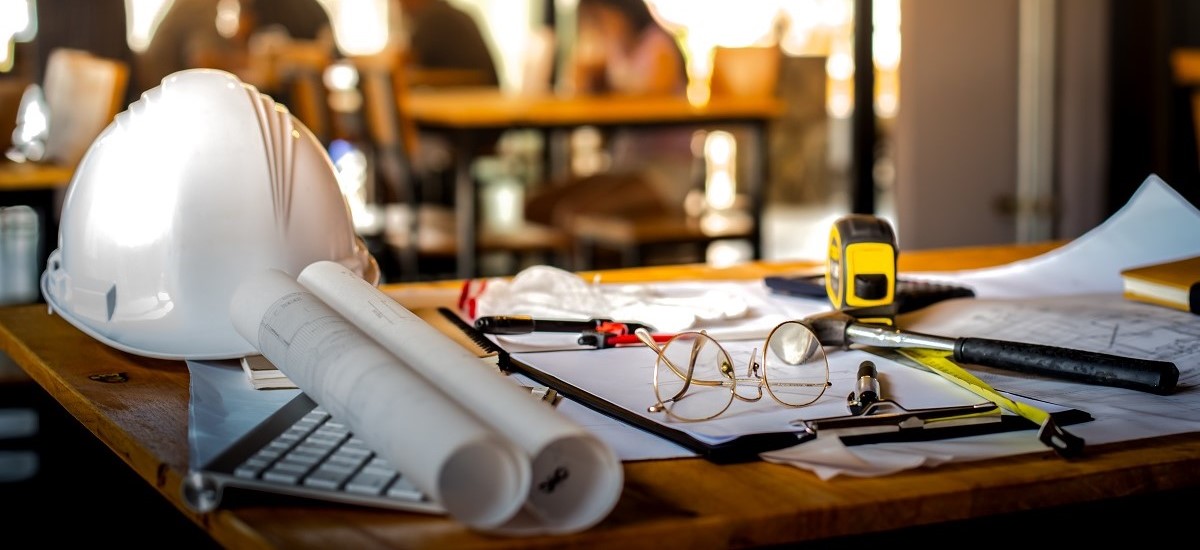 Hardhat, schematics, measuring tools and architect's tools on a desk