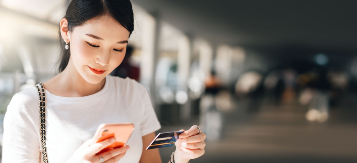 young-woman-holding-credit-card-checking-phone-at-airport