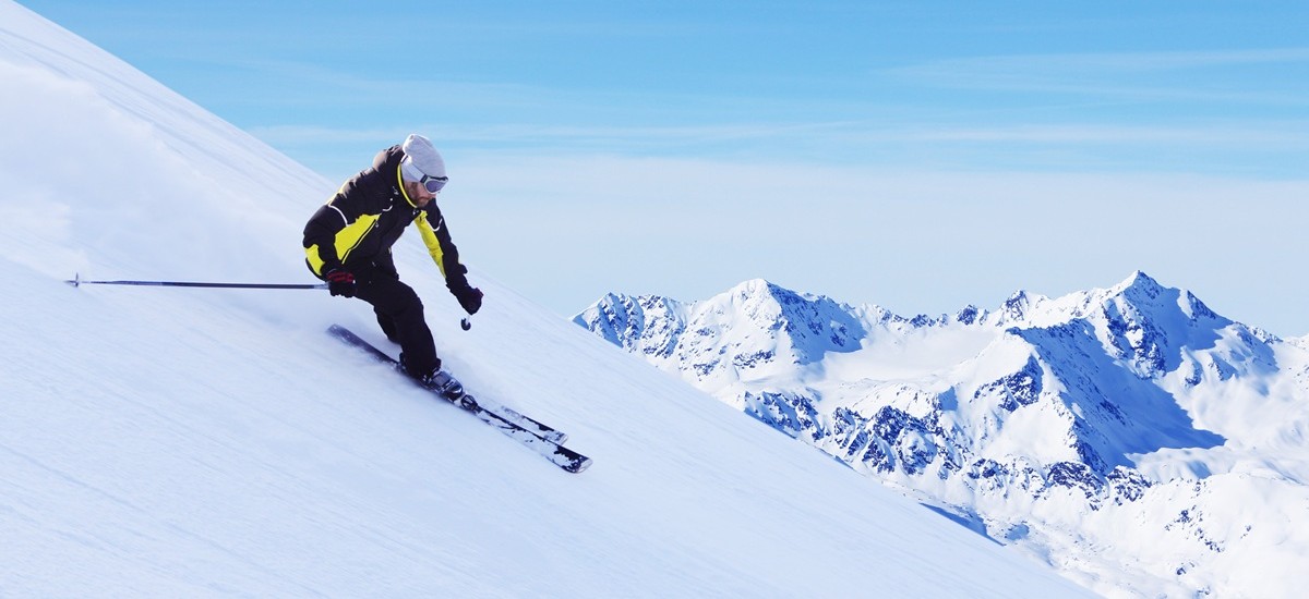 skier in red traversing down a snowy mountain