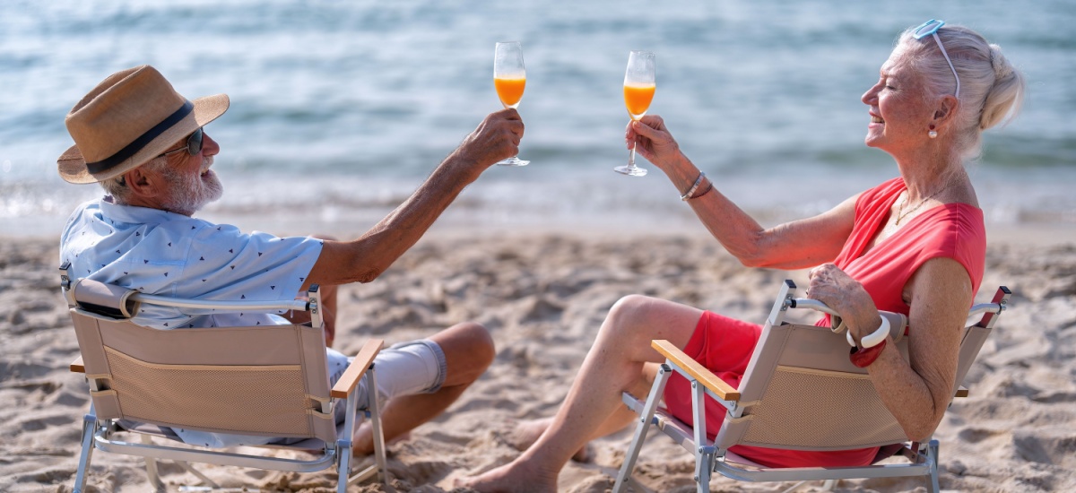 older-couple-sitting-on-beach-drinking