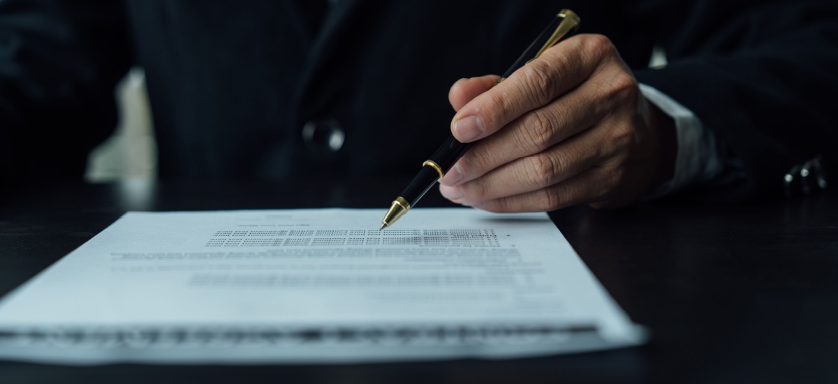 man-holding-a-pen-going-over-legal-documents