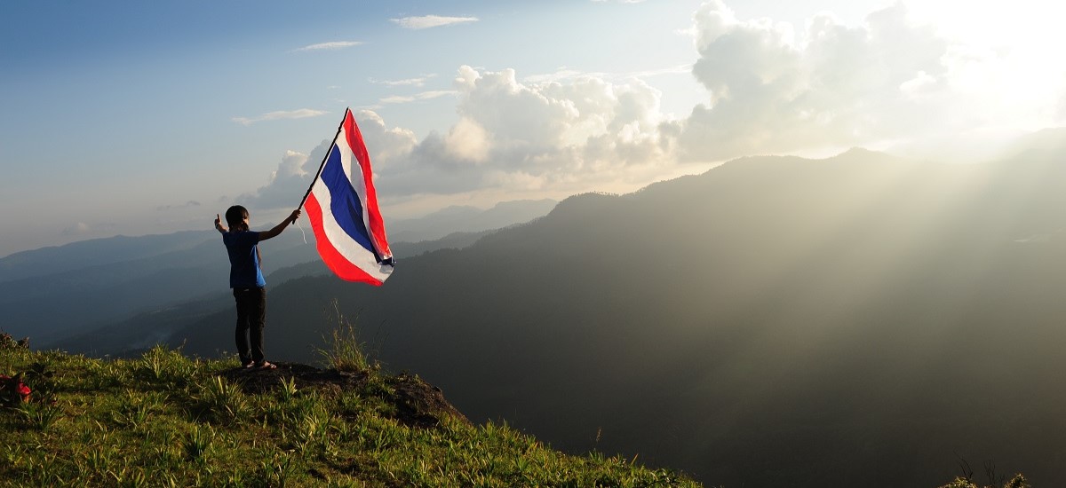 Thai flag flying over vista of Thailand