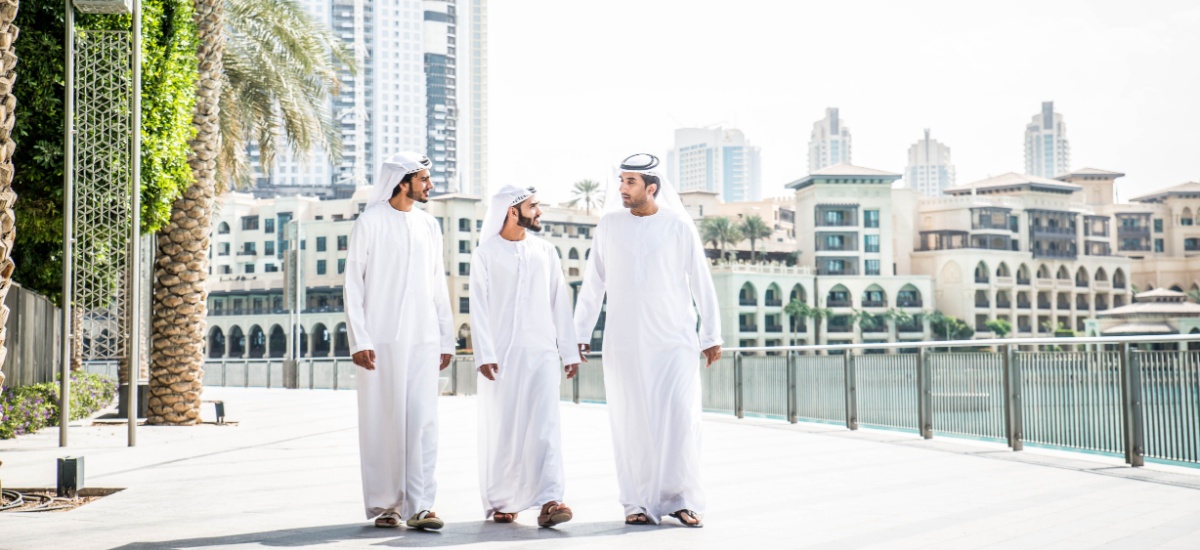 three Arab men in white kandura or dishdasha walking in a street in Dubai