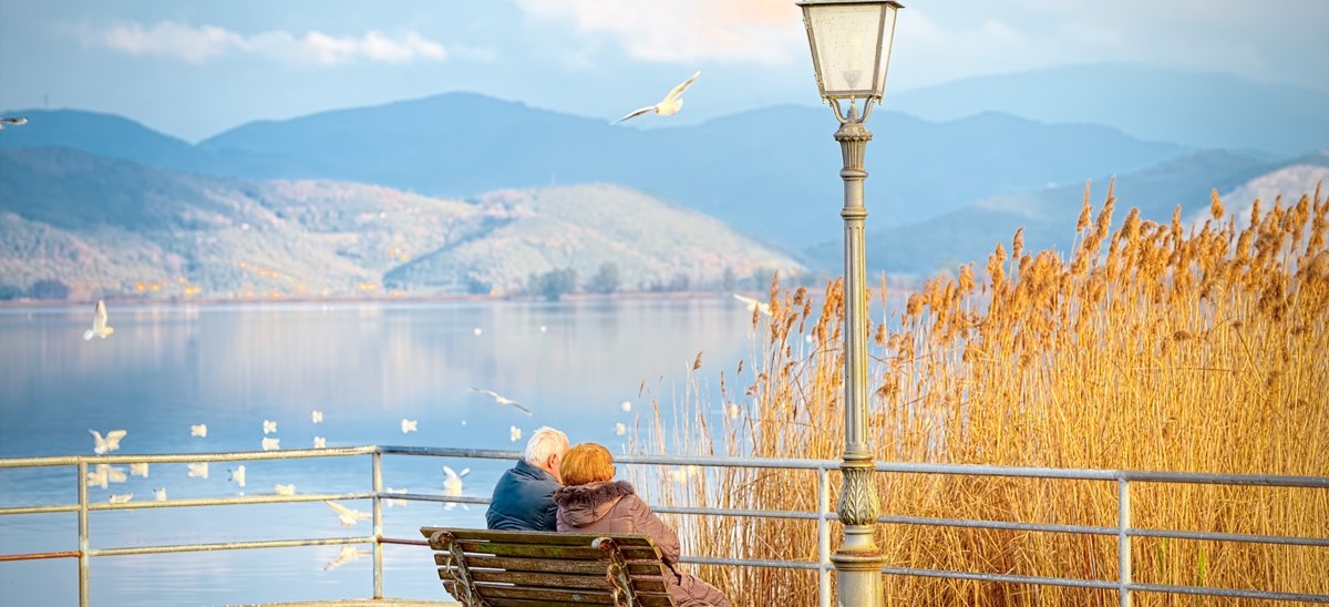 elderly vouple sitting on a bench in Tuscany overlooking a lake