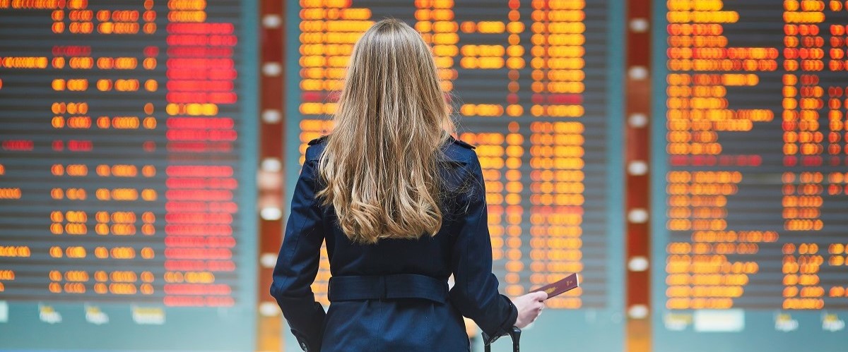 Woman standing in front of departures board at an airport
