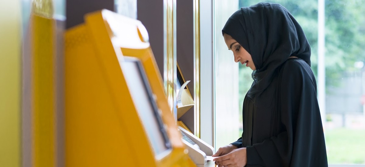 Arab woman in black abaya at an ATM