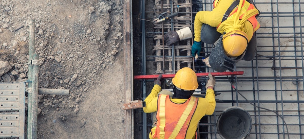 Top down view of two construction workers laying the foundations for a bulding