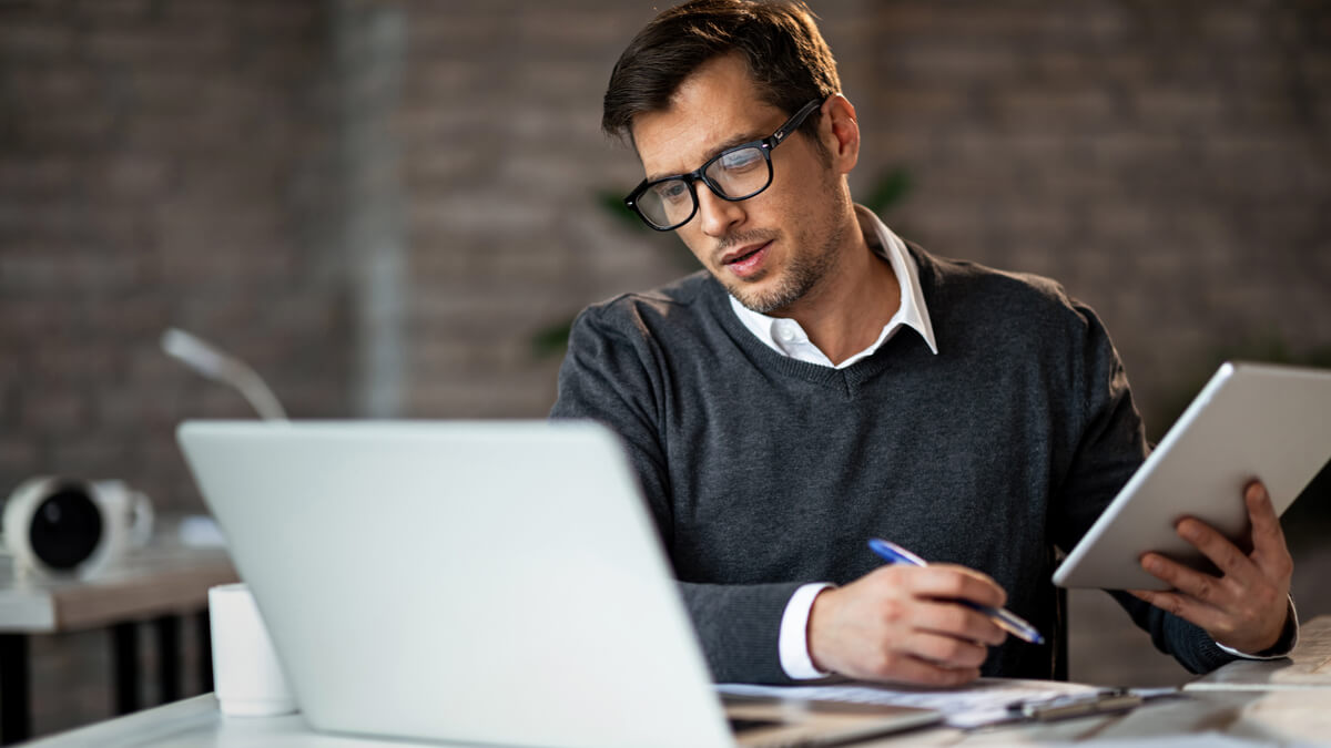 man-working-on-laptop-and-holding-a-tablet