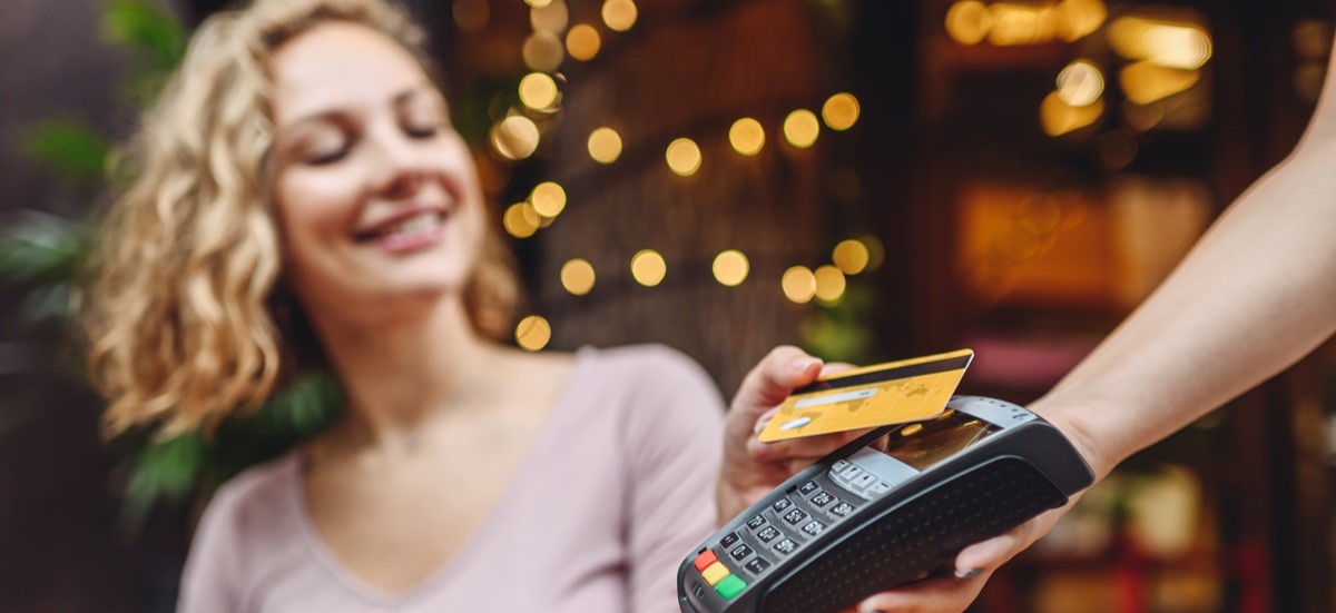 Smiling blonde woman using her card to pay for coffee