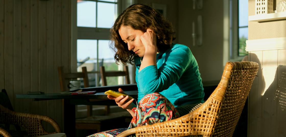 A woman at home looking down on her phone